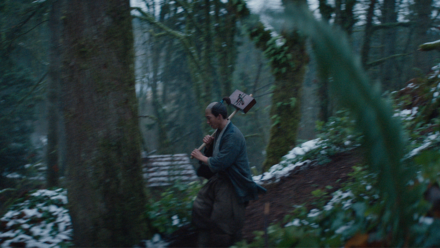 A messenger runs down a forest path carrying a box