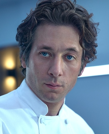 Jeremy Allen White headshot in a white chef jacket.
