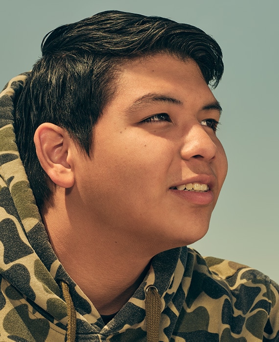 Lane Factor headshot wearing a camouflage hoodie with the sky in the background.