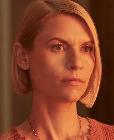 Claire Danes headshot in salmon colored top with dainty gold necklace, half face illuminated by golden soft light