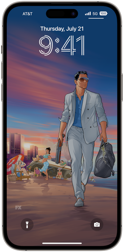 Archer wearing a gray suit, holding a duffle bag, and walking on the beach with the cast hanging out in the background