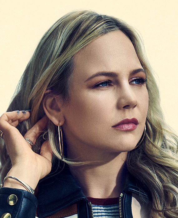 Adelaide Clemens headshot wearing a striped shirt and large earrings