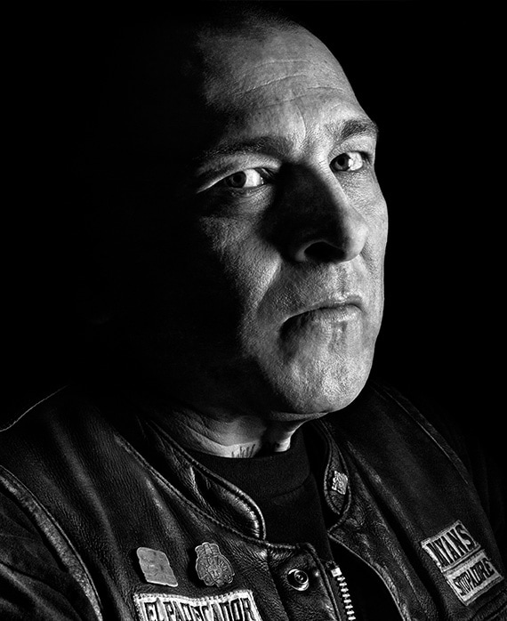 Frankie Loyal headshot wearing a Mayans leather jacket with pins and a black shirt