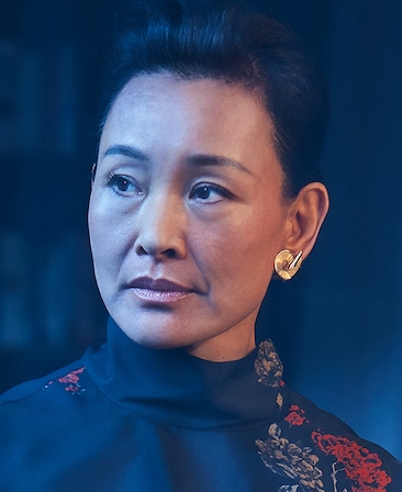 Joan Chen wearing a gold earring and high neck top