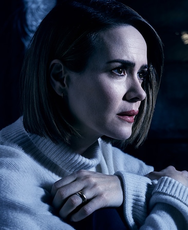 Sarah Paulson in white turtleneck with hands crossed over chest, wearing gold wedding band under moonlight shining over her