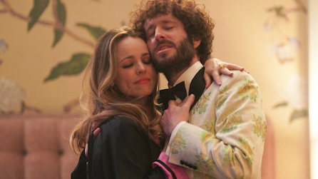 Dave Burd and Rachel McAdams, dressed up, hugging each other. 