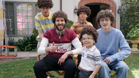 Dave holding a thumbs up next to young kids dressed like him