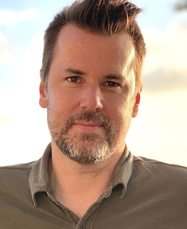 Headshot of executive producer of FX's Necaxa, George Gewey, wearing a brown button up.