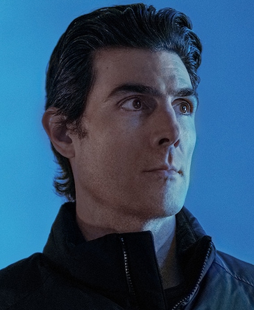 Louis Cancelmi headshot wearing a black puffy jacket standing against a blue background