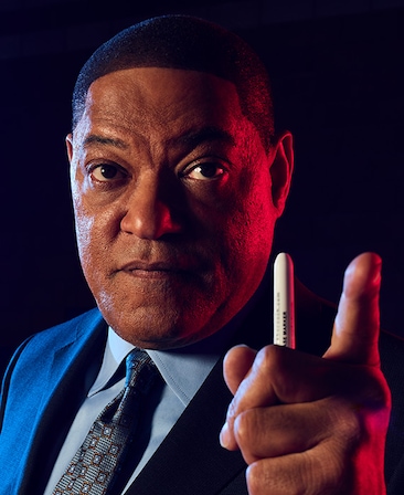 Laurence Fishburne as Doc Rivers in FX's Clipped wearing a suit, holding a pen pointing.