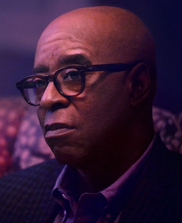Courtney B. Vance as Marshall Tryon in FX's Grotesquerie in a suite wearing brown glasses sitting on a patterned couch.