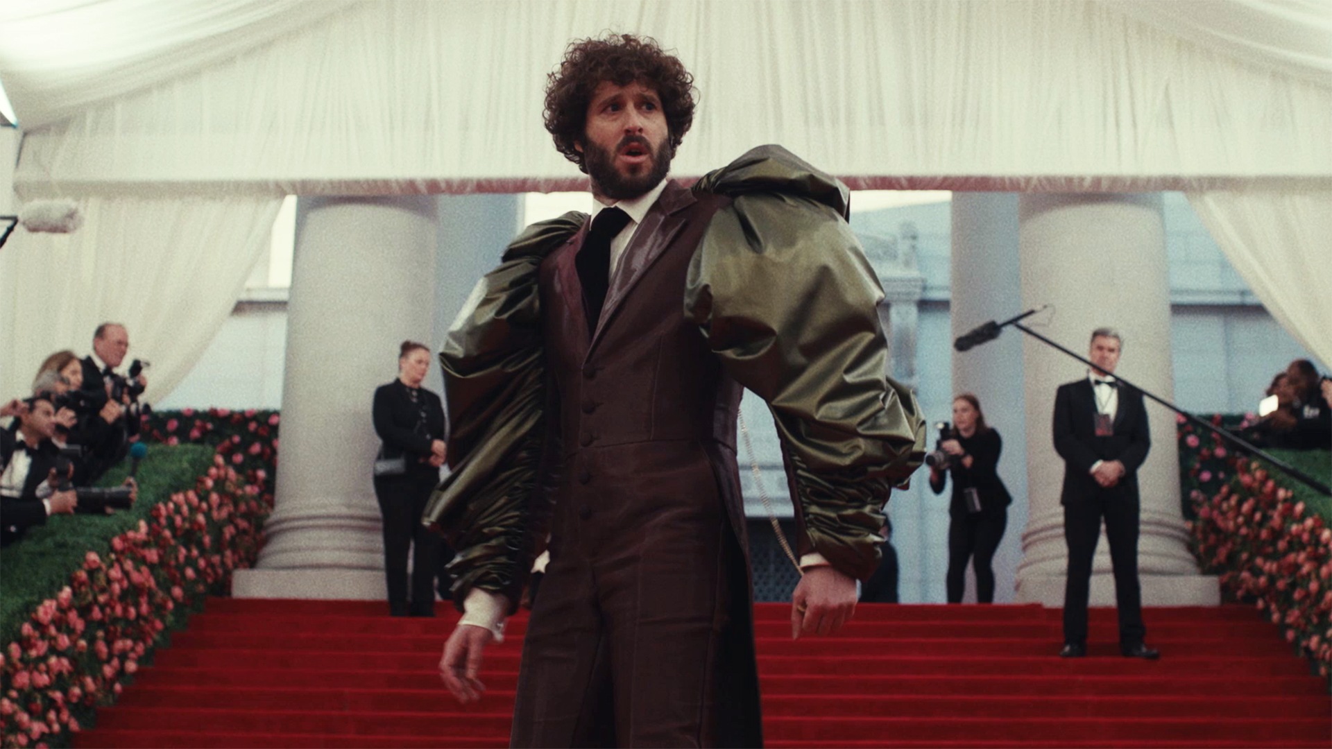Dave standing on a flight of red stairs wearing a suit with puffy sleeves