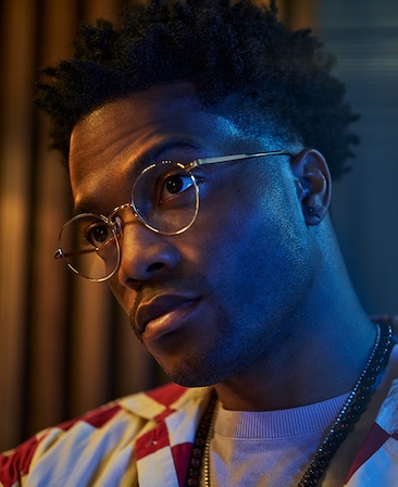 Jermaine Fowler headshot wearing glasses and a red and white checkered jacket