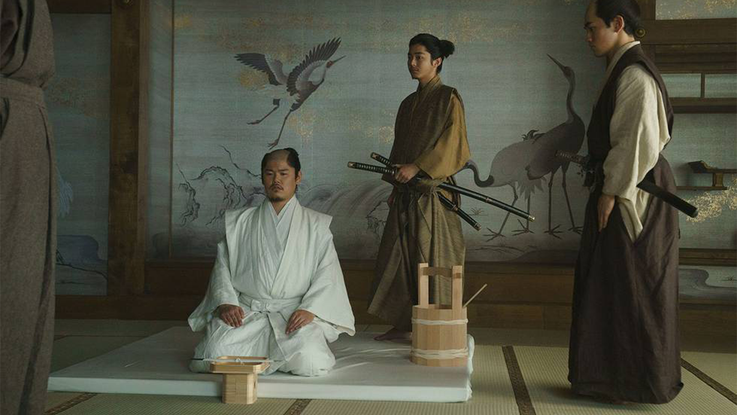 Tadayoshi prepares for his seppuku dressed in white while Nagakado stands behind him ready to assist