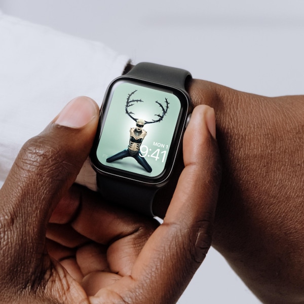 Man wearing Apple Watch with lock screen of person wearing black antlers and knees stretched in black pants for FX'S AHS NYC