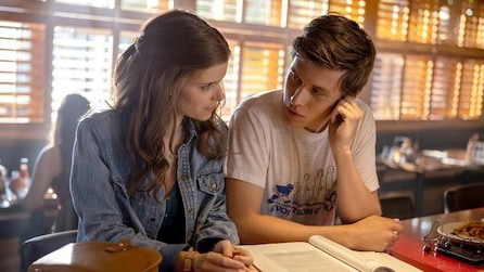 Kate Mara and Nick Robinson sitting next to each other with a book open on the table