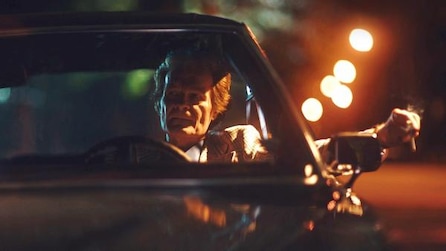 Man driving a car with hand out the window holding a cigarette