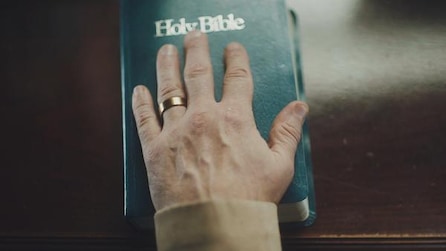 A hand, with a ring on the wedding finger, placed on the Holy Bible