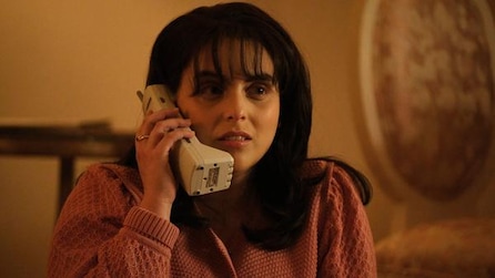 Beanie Feldstein as Monica Lewinsky wearing pink sweatshirt talking on the phone in American Crime Story Impeachment