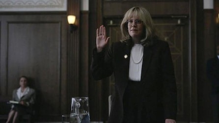 Sarah Paulson as Linda Tripp holds right hand up in a courtroom in American Crime Story Impeachment