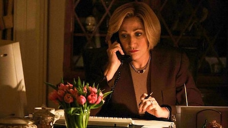 Edie Falco as Hillary Clinton holds phone to her ear with pen in her hand by a computer in American Crime Story Impeachment