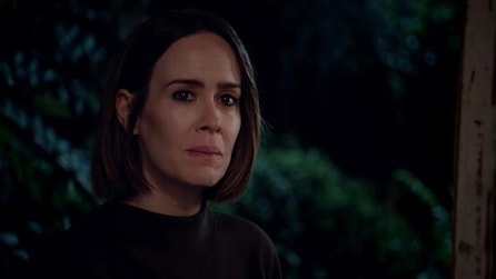 Sarah Paulson as Ally standing outside at night wby doorway looking grim in American Horror Story Cult