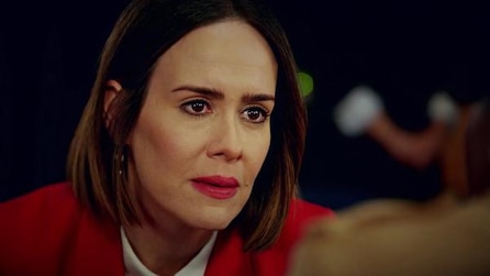Sarah Paulson as Ally wearing pink lipstick and red blazer looking concerned in American Horror Story Cult