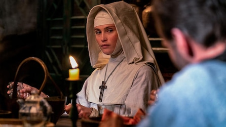 Gemma Arterton as Sister Clodagh at dining table with candle looking over at obscured man in blue in FX's Black Narcissus