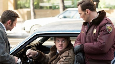 Patrick Wilson as Lou in puffer police jacket with man in grey suit pulling over man in blue car in FX's Fargo Year Two