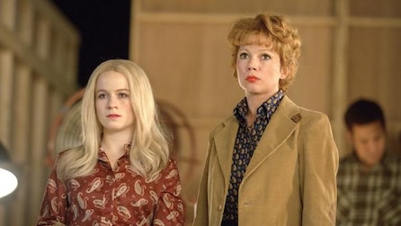 Michelle Williams as Gwen Verdon in trench coat standing with blonde girl in red shirt on film studio set in FX's Fosse/Verdon