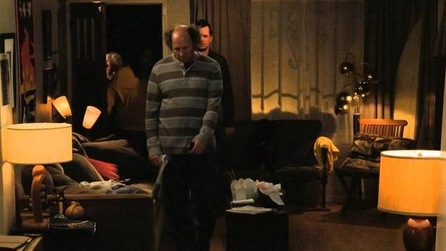 Dan Bakkedahl as Steve standing in living room with Jim Jefferies staring in background with lamps on in FX's Legit