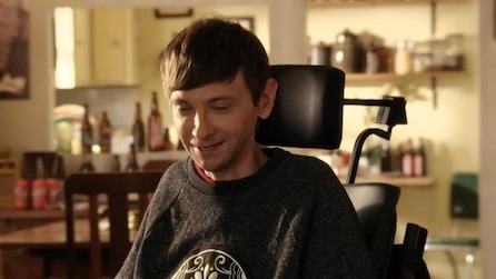 DJ Qualls as Billy in wheelchair smiling with eyes closed in living room in FX's Legit