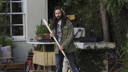 Man holding a broom in a backyard