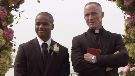 A priest and a man in a suit standing next to each other 