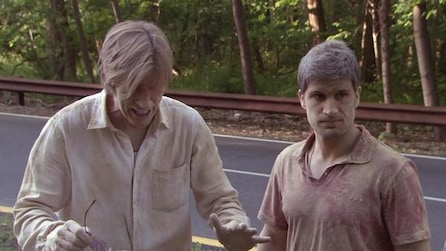 Two men covered in dirt standing on the side of the road