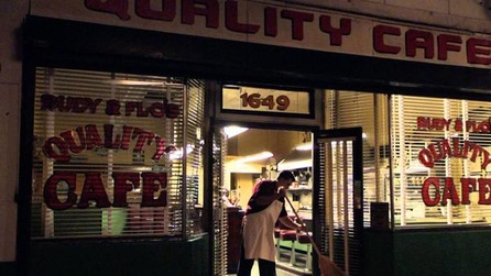 Man sweeping the floors of a shop named "quality cafe"