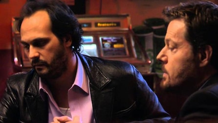 Two men with serious looks on their face standing next to an ATM machine