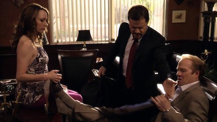 Man sitting while his legs are perched up on the desk as a woman holds his feet