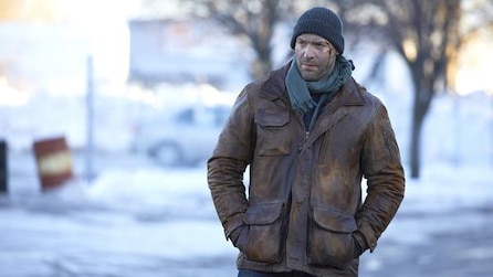 Man standing outside wearing a beanie, scarf and brown jacket