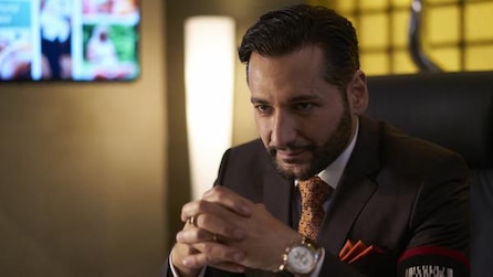 Man sitting with his hands claps wearing a suit and a nice watch