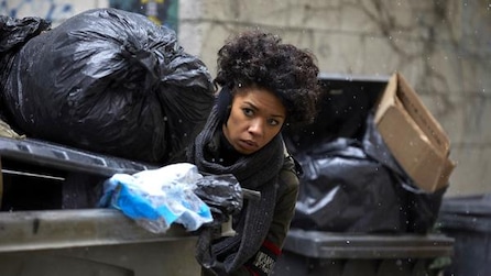 Woman hiding between trash cans full of trash bags
