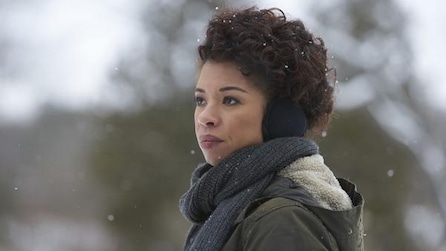Woman standing in the snow wearing ear muffs and scarf