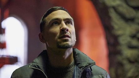 Man wearing a green jacket and staring up at the ceiling