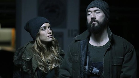 A man and woman both wearing beanies and dark clothing