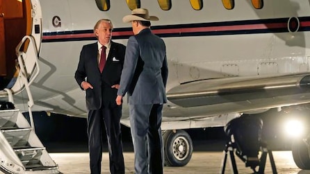 Two men talking while standing beside a plane