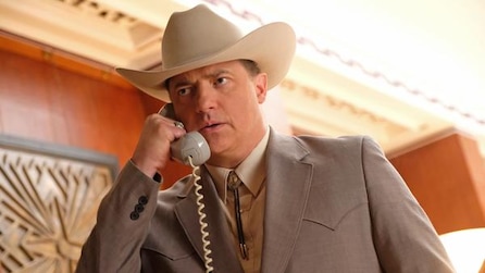 A man wearing a cowboy hat while talking on the phone 