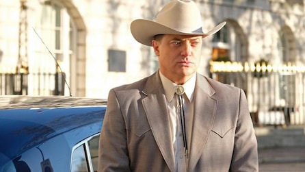 Man standing outside a car wearing a cowboy hat