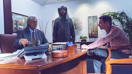 Three men sitting in an office, while one is dressed up as a dog