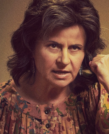 Tracey Ullman headshot wearing a patterned blouse and holding a fist with her hand