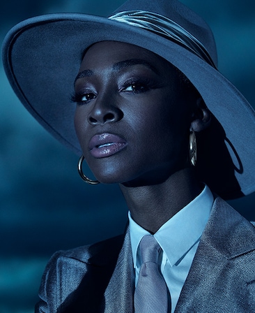 Headshot of Angelica Ross in grey suit and hat under moonlight of cloudy night from FX's AHS Double Feature